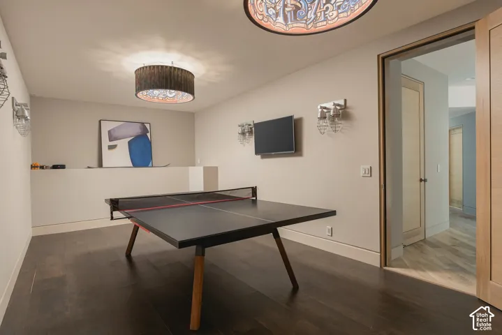 Recessed ceiling with two distinct light fixtures, dark wood-finish flooring, and a half-wall partition