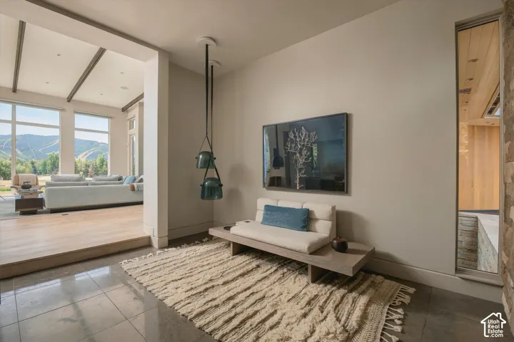 Polished concrete flooring, recessed lighting, accent wall with stone facade, vaulted ceilings, and large picture windows
