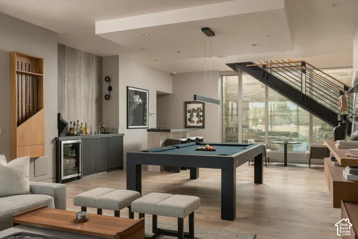 Wood-finish flooring, built-in wet bar, modern staircase with metal railings, recessed lighting, and large format windows