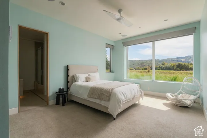 Expansive window offering a mountain backdrop, recessed lighting, ceiling fan, and carpeted flooring