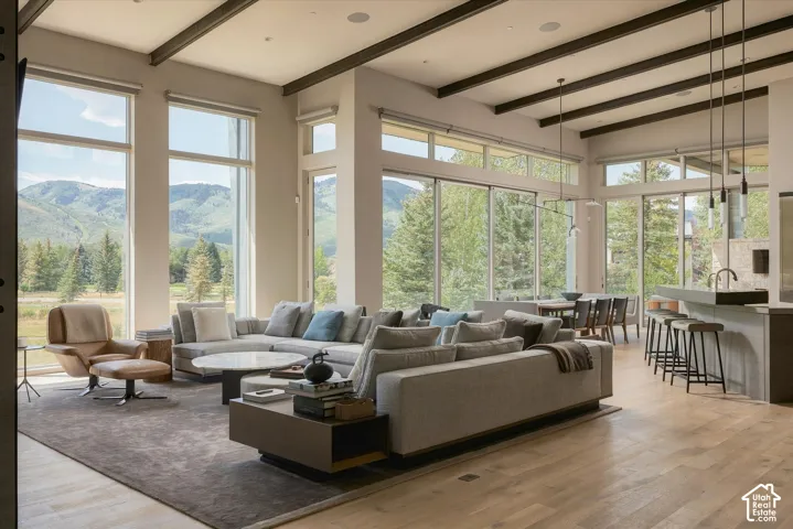 Expansive open-concept space featuring wood-finish flooring, exposed ceiling beams, and a kitchen island with seating