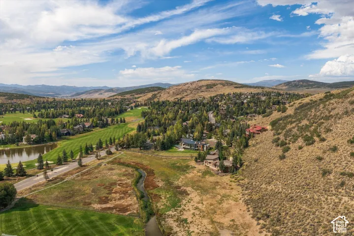 Expansive golf course setting with a tranquil pond, mature trees, and mountainous terrain