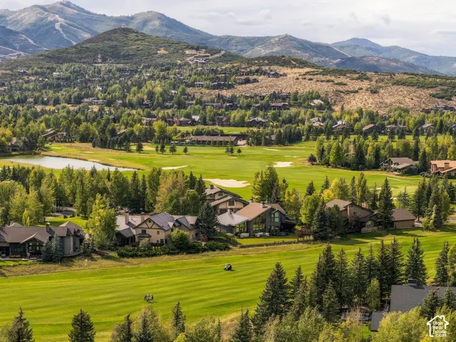 Expansive golf course with surrounding residential properties, mature trees, and mountainous terrain