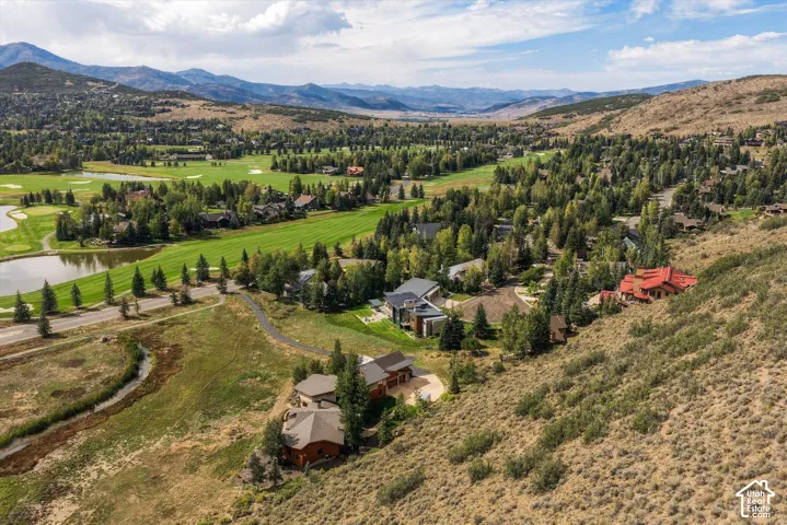 Expansive landscape featuring golf course fairways, multiple water features, mature trees, and mountainous terrain