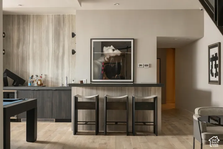 Wet bar with integrated sink, wood-finish flooring, recessed lighting, and built-in cabinetry