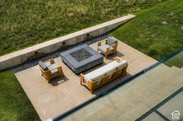 Hardscaped patio with a built-in fire pit, surrounded by a concrete retaining wall with integrated lighting