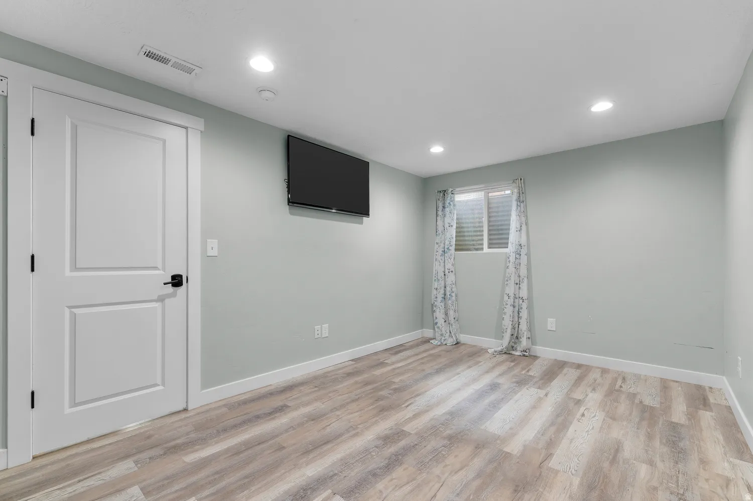 Room with wood-finish flooring, recessed lighting, and light-toned walls