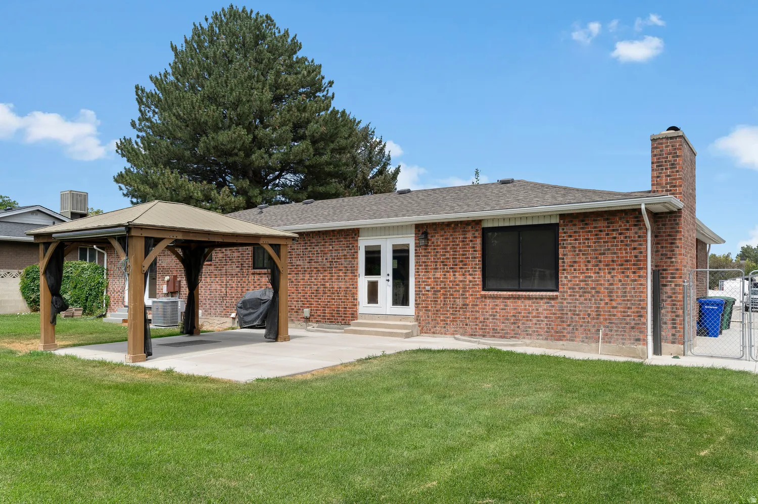 Expansive backyard featuring a large concrete patio with a wooden gazebo, a red brick exterior, and spacious RV Parking