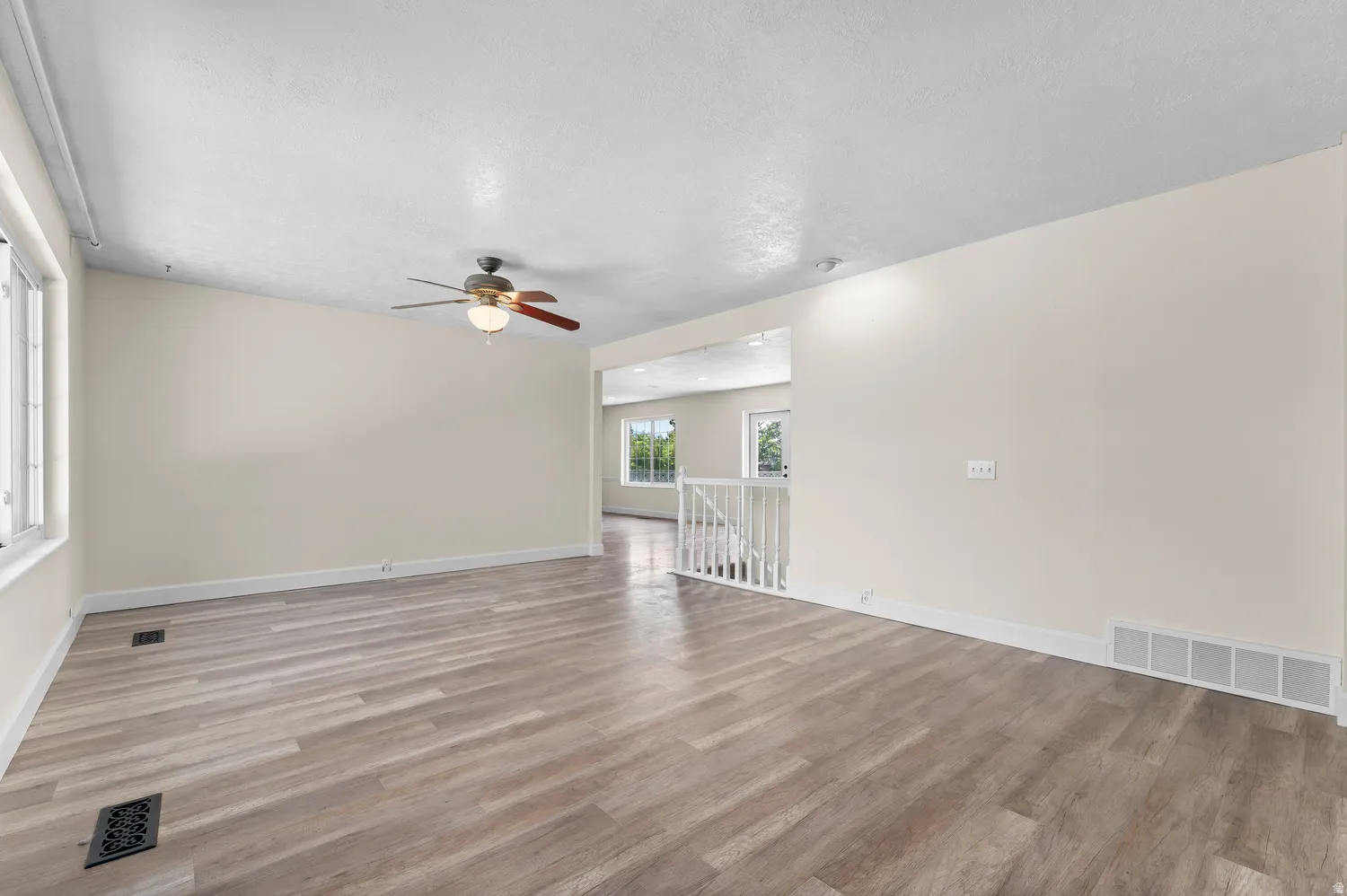 Spacious room featuring wood-finish flooring, light-toned walls, and natural lighting.