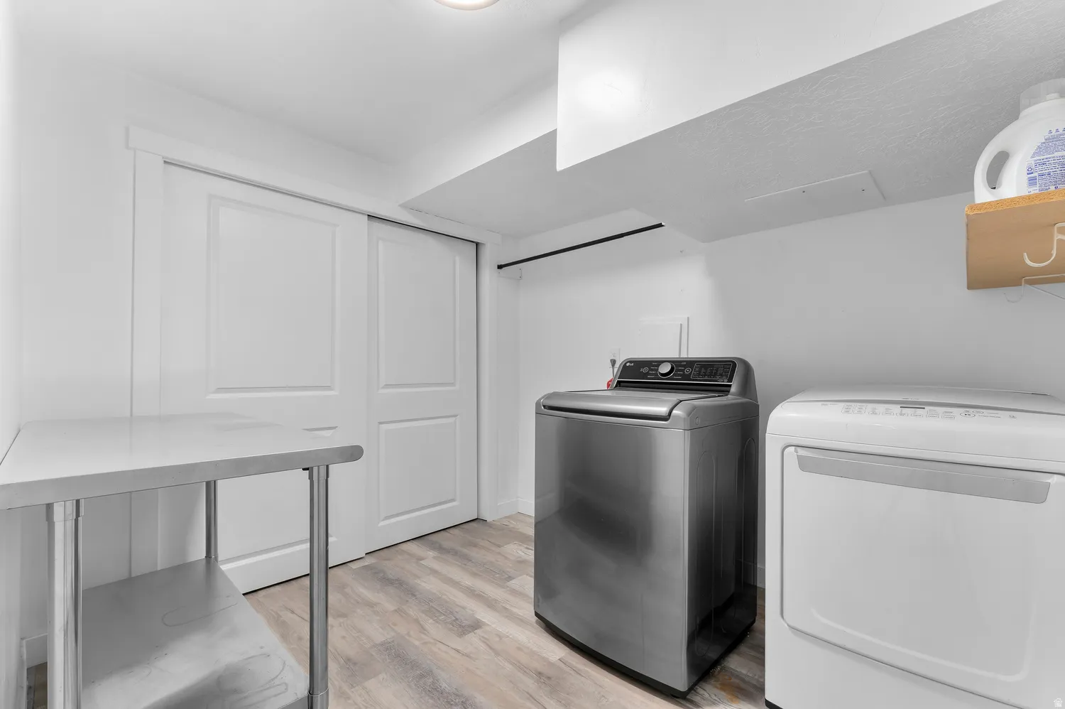 Dedicated laundry area featuring wood-finish flooring, bright white walls, and a recessed ceiling light