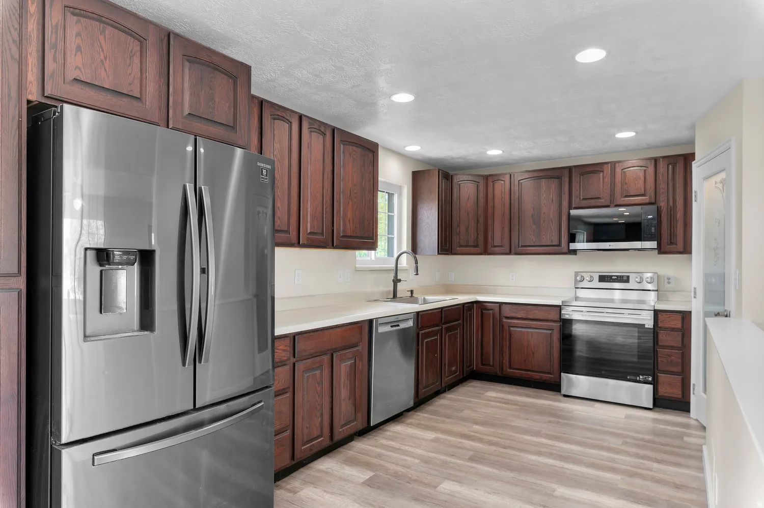 Modern kitchen featuring wood-finish cabinetry, light countertops, and stainless steel appliances
