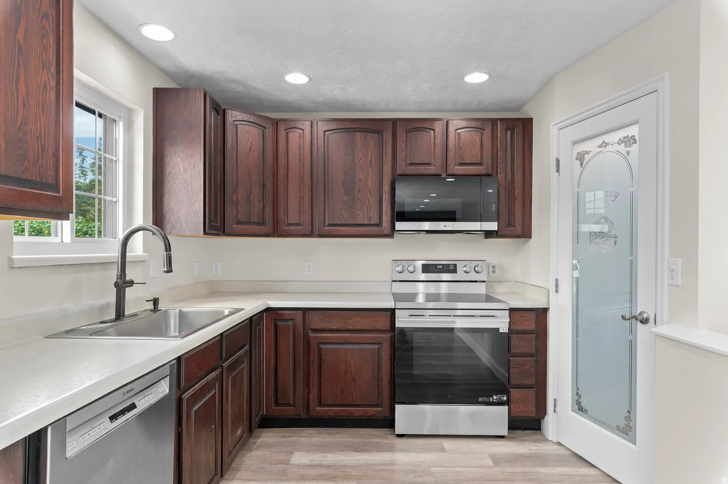Kitchen featuring rich wood cabinetry, light countertops, and brand new Range and Microwave.