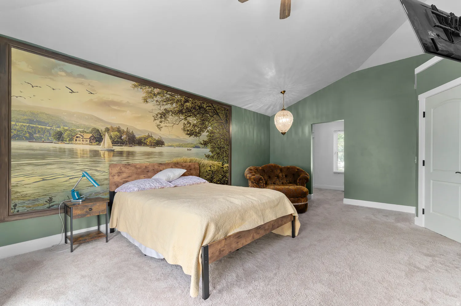 Spacious  Master bedroom featuring a prominent framed wall mural, vaulted ceiling, and neutral carpeting