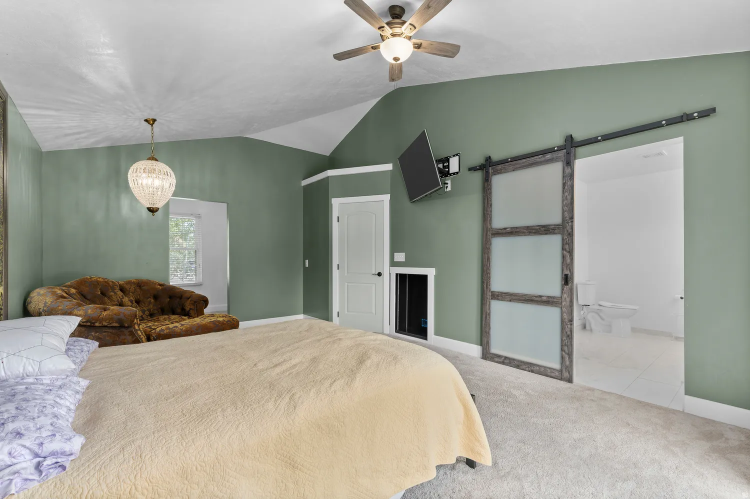 Spacious room featuring vaulted ceilings, a ceiling fan with integrated lighting, and carpet flooring