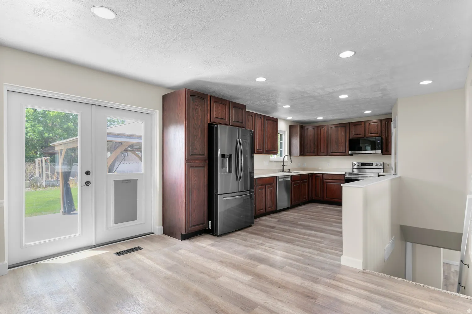 Kitchen featuring wood-finish flooring, dark wood cabinetry, stainless steel appliances, and recessed lighting
