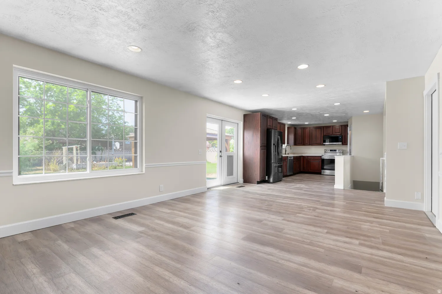 Open-concept living space featuring wood-finish flooring, recessed lighting, and a large window