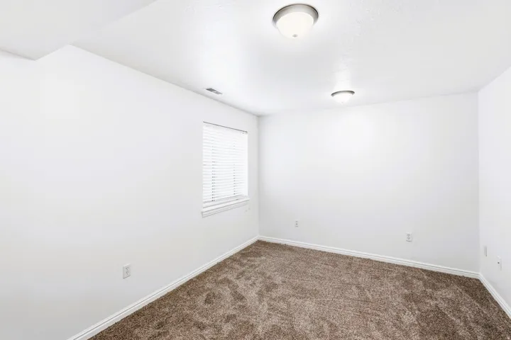 Living room/ Den, featuring freshly painted white walls, new carpeting, and white baseboards