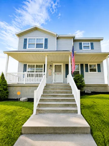 Two-story residence featuring light gray siding with blue window shutters. This photo has been AI enhanced.