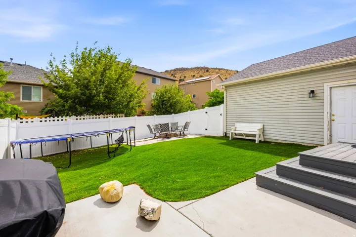 Fully Landscaped backyard featuring artificial turf, concrete patio, white privacy fencing, Trex decking and exterior access to the property