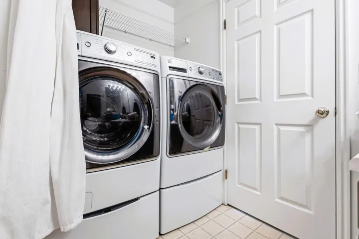 Laundry area featuring a front-loading washer and dryer set, elevated by pedestals