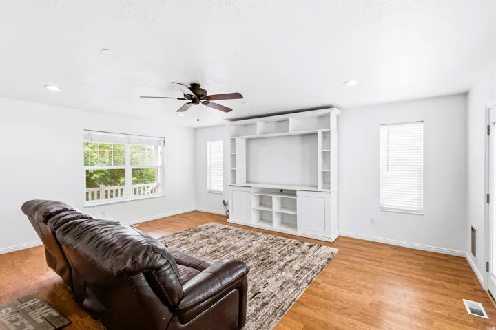 Living room featuring laminate flooring, ceiling fan and fresh paint.