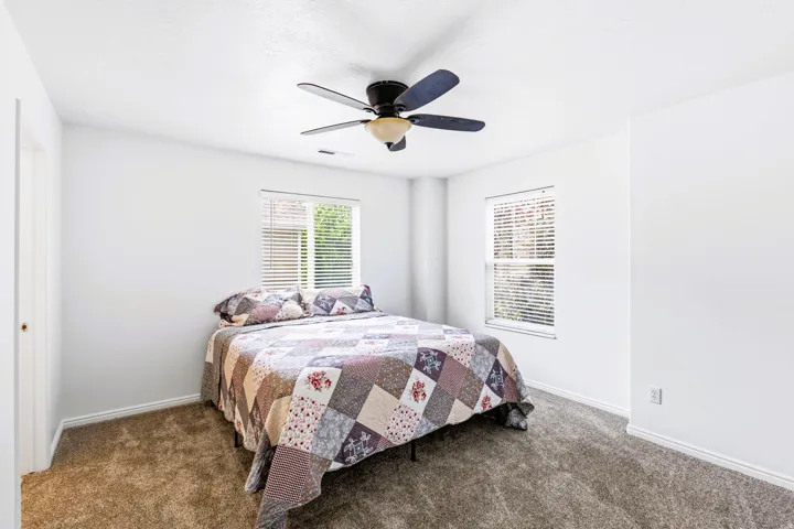 Primary Bedroom featuring two windows with blinds, a ceiling fan with integrated lighting, and neutral-toned carpeting