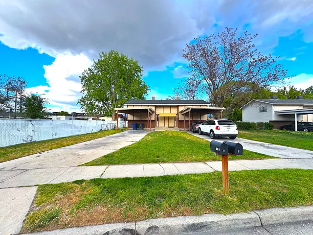 Duplex property featuring two distinct carports, a shared central lawn, and individual concrete driveways