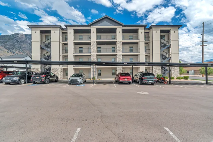 Multi-story residential building featuring stone and stucco facade, individual balconies with metal railings, and exterior staircases