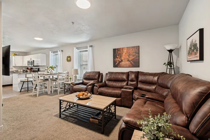 Open-concept living area featuring light-colored walls and carpet flooring