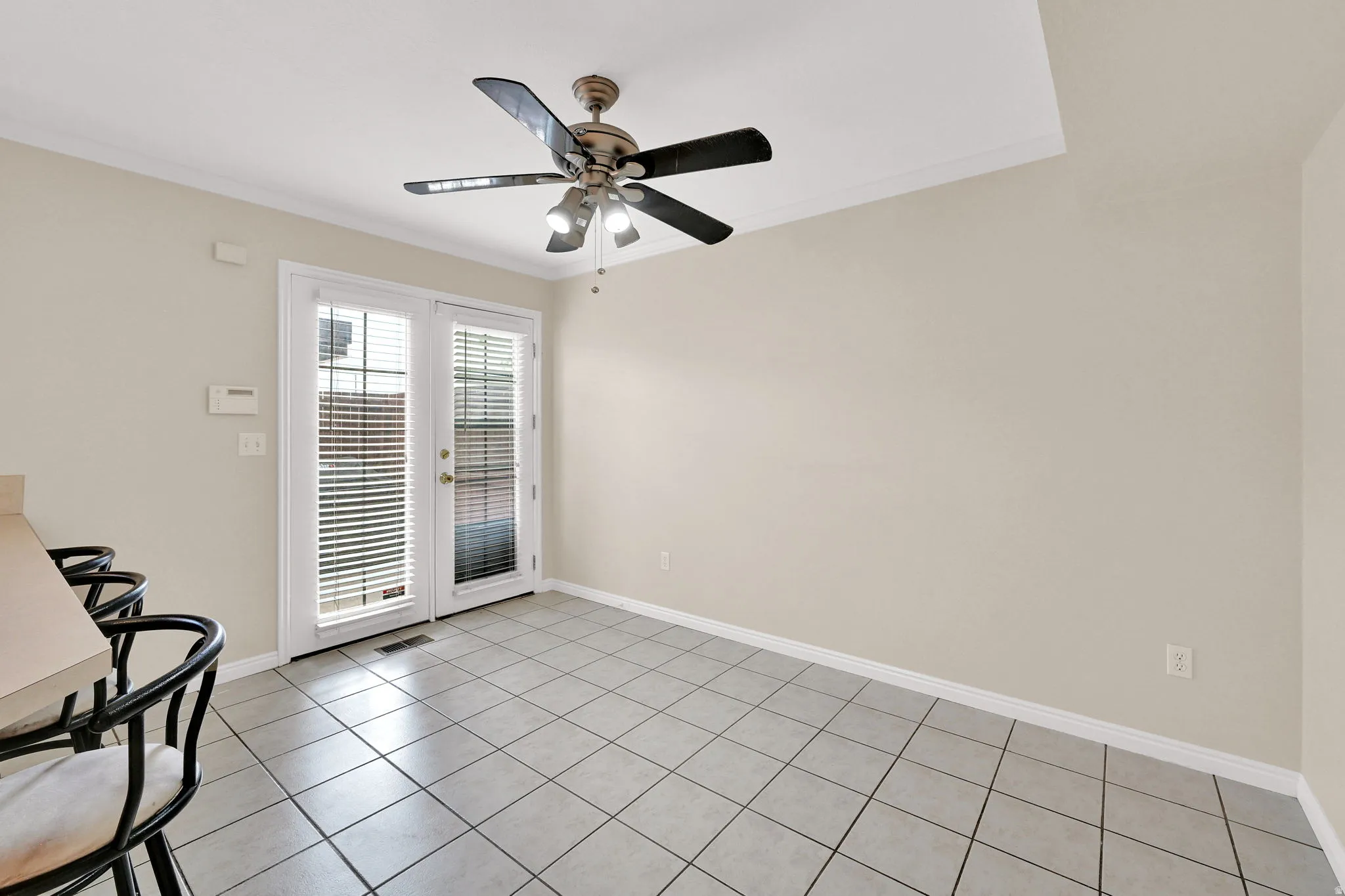 Dining space featuring tile flooring, neutral wall tones, and crown molding
