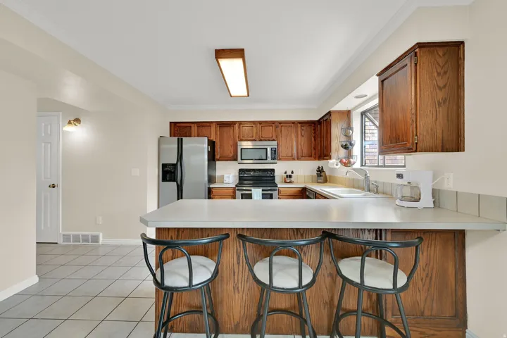 Kitchen featuring wood cabinetry, stainless steel appliances, a breakfast bar, and tile flooring