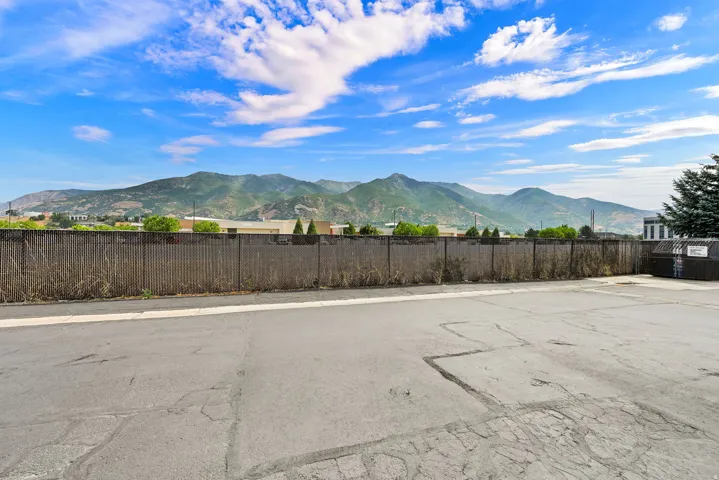 Paved lot with chain-link fencing and mountain scenery