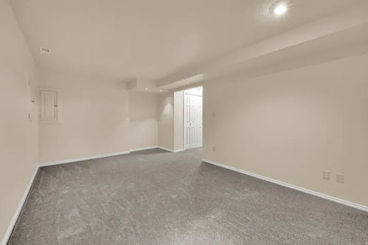 Spacious room featuring neutral carpeting, light-toned wall paint, recessed lighting, and white baseboards