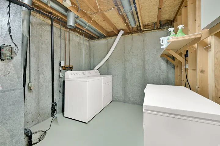 Basement utility area featuring exposed concrete walls and an unfinished wood ceiling