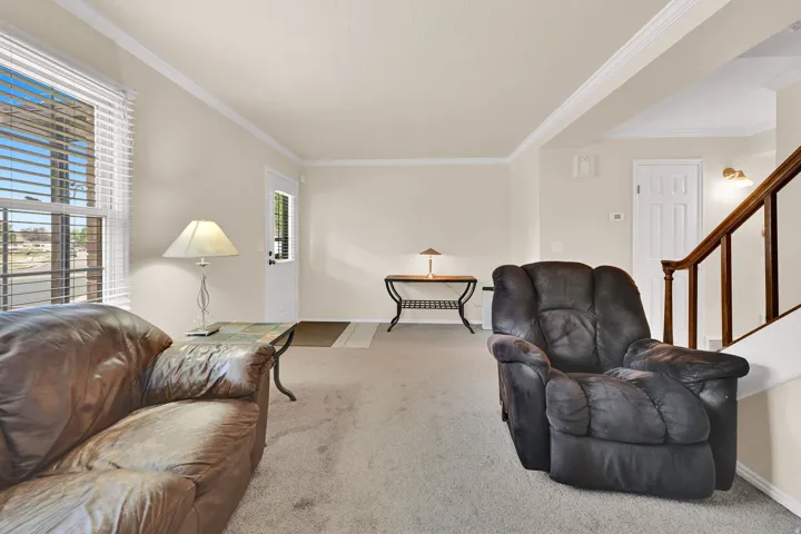 Carpeted living area with neutral wall tones and crown molding