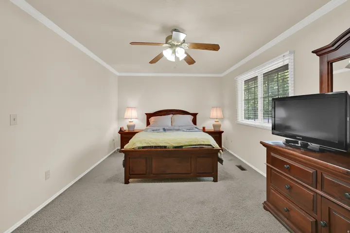Carpeted room featuring crown molding and a ceiling fan