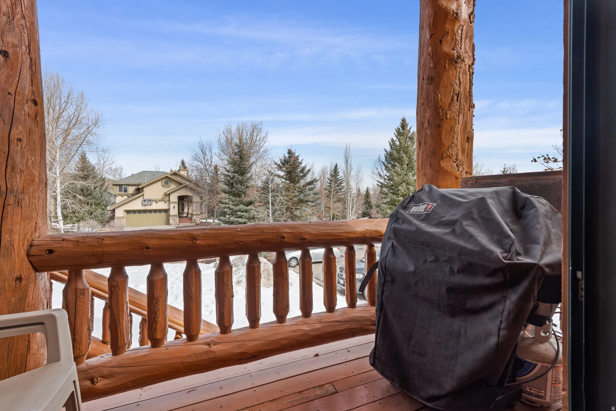 Expansive exterior deck crafted from substantial natural logs, featuring a robust log railing and exposed wood flooring