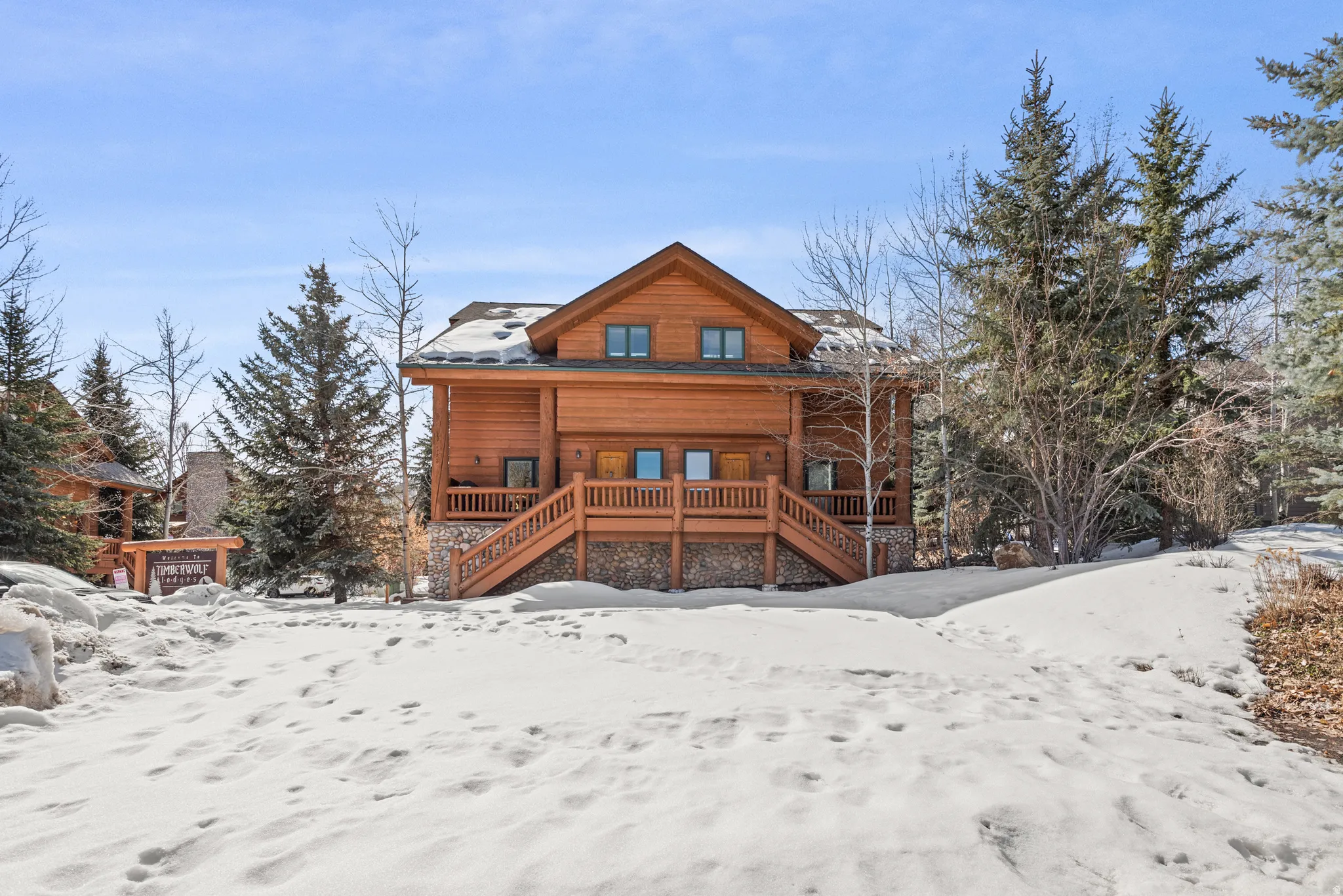 Log cabin exterior featuring robust wood construction, a stone foundation, and multiple windows