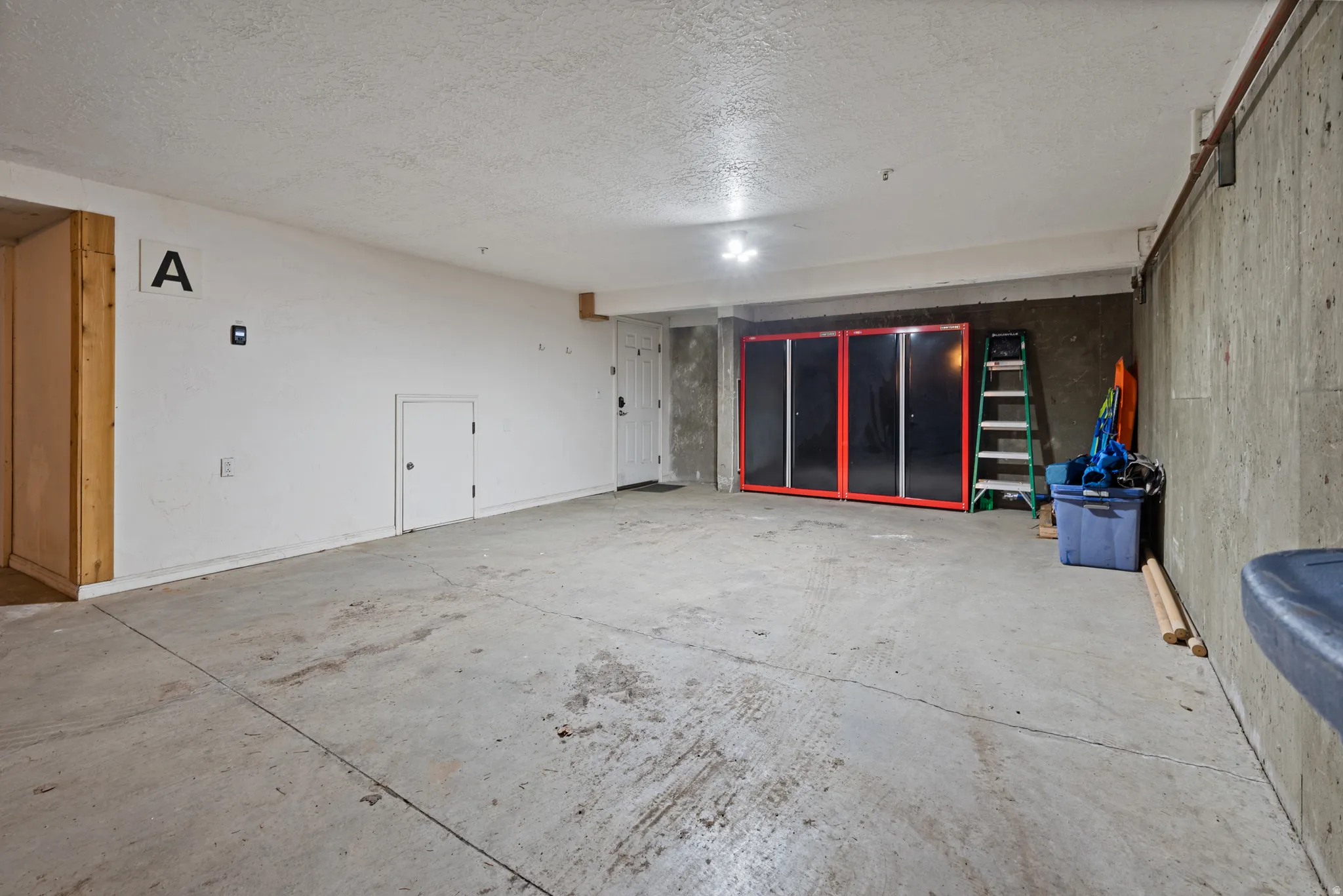 Spacious garage with concrete flooring and exposed concrete wall