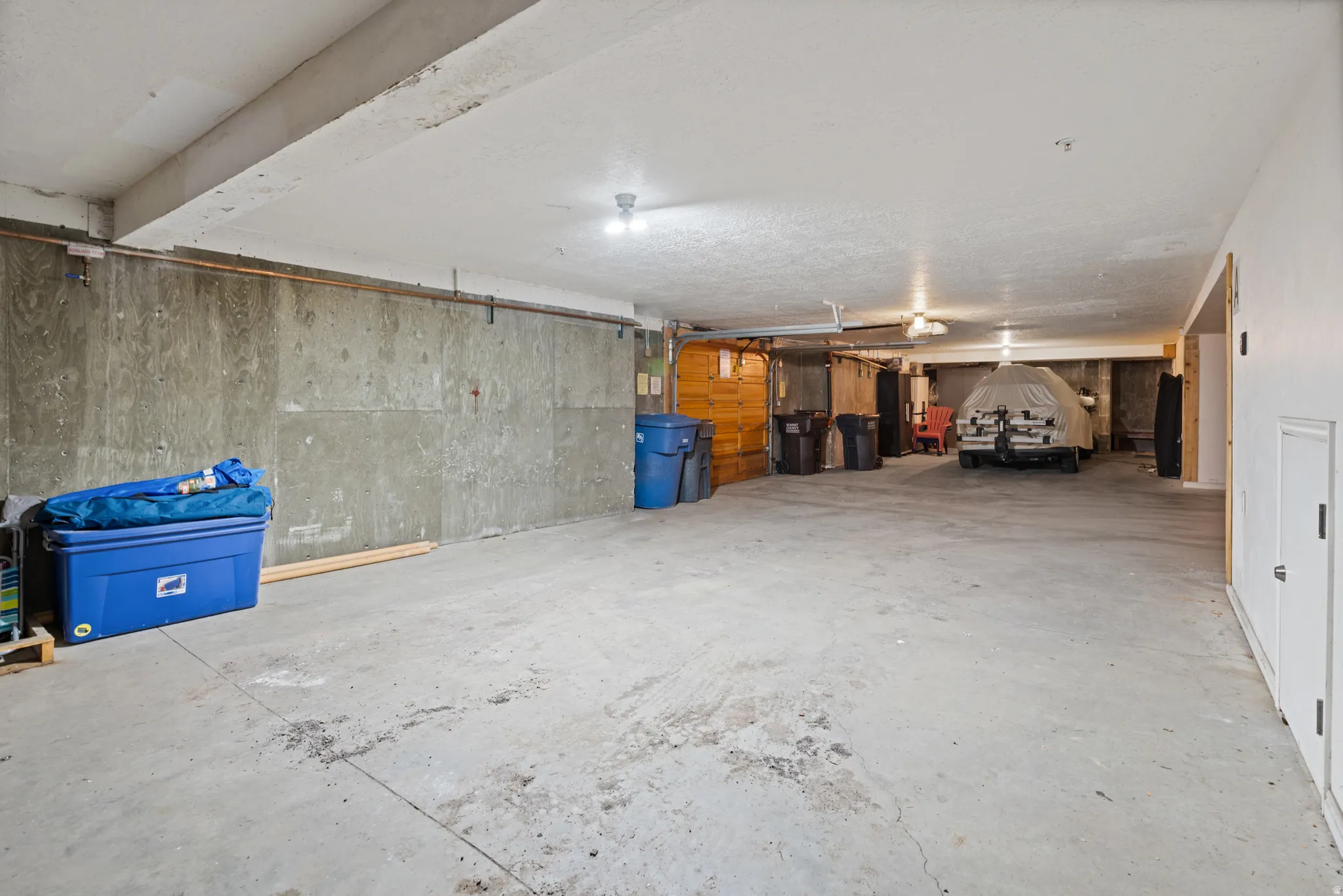 Expansive concrete floor surface in a multi-use area featuring plywood wall paneling, a white painted ceiling, and recessed lighting fixtures