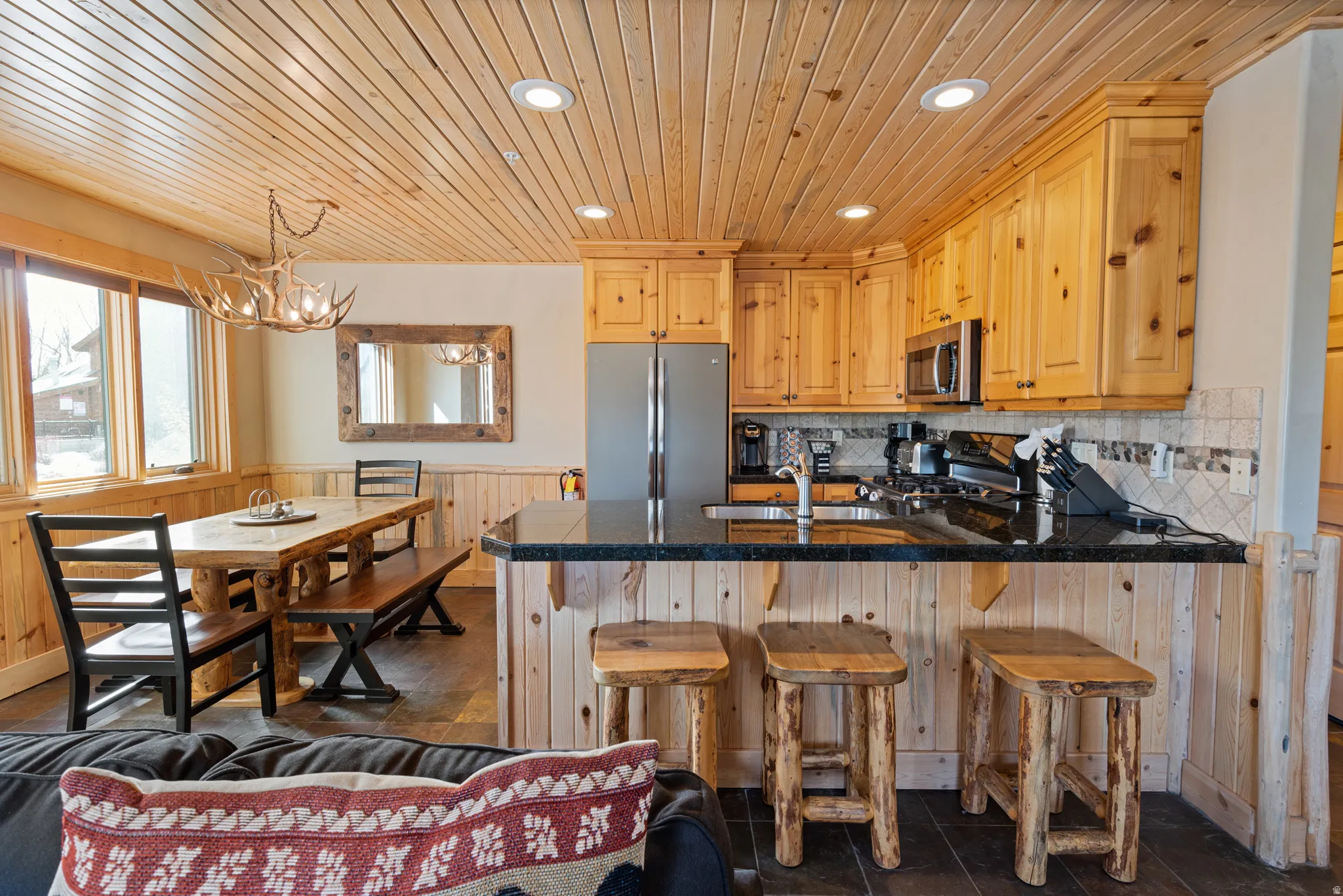 Kitchen featuring black granite countertops, stainless steel appliances, wood-finish flooring, and recessed lighting