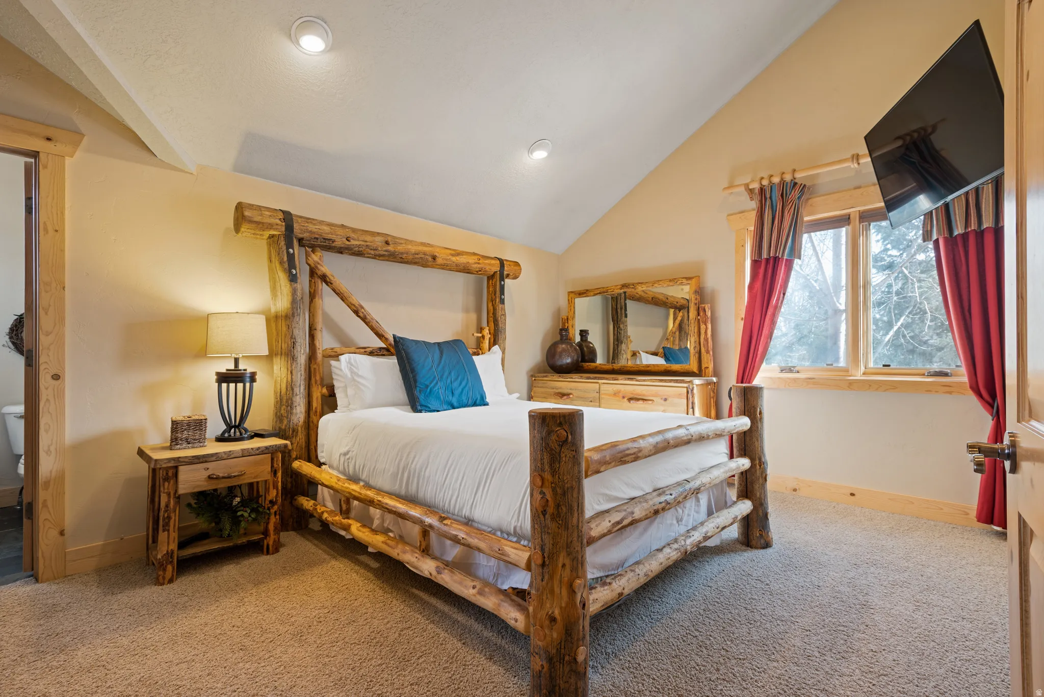 Vaulted ceiling bedroom featuring natural wood trim, recessed lighting, a large window, and carpet flooring