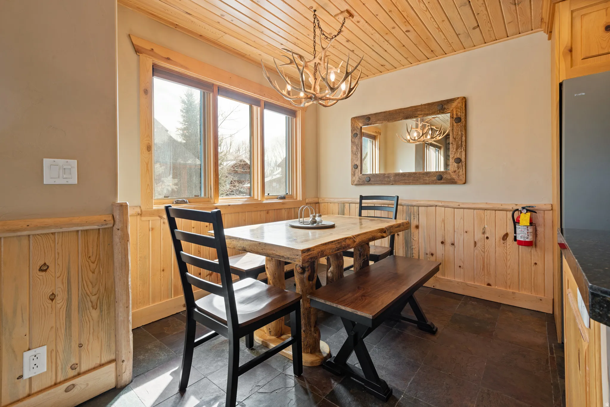 Dining area featuring wood-finish flooring, three windows with natural wood trim, and a wood-paneled ceiling