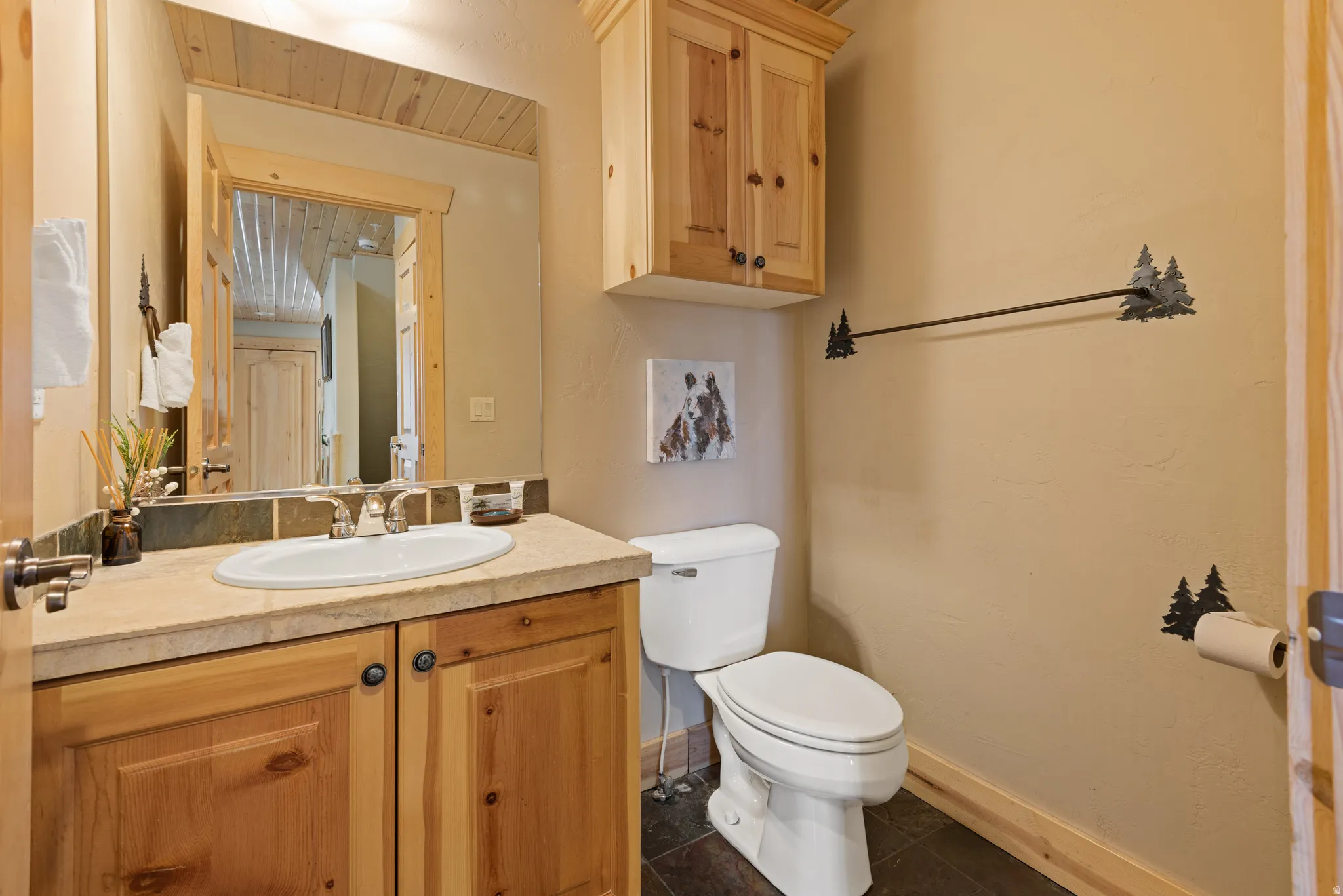 Bathroom featuring a wood vanity with a solid surface countertop, an oval undermount sink, and a tiled backsplash