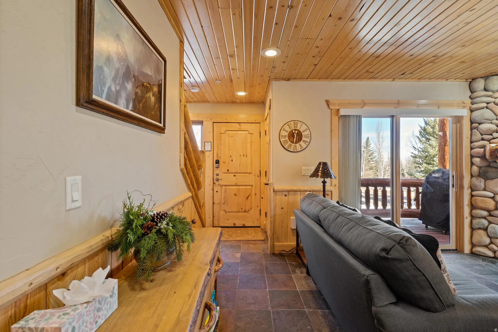 Entryway featuring wood-paneled walls and ceiling, slate-finish flooring, and a solid wood front door