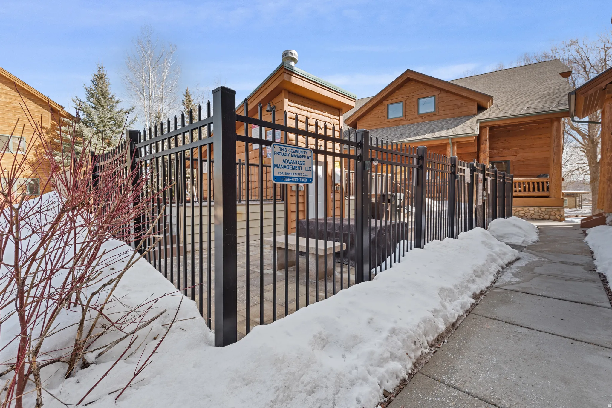 Paved walkway alongside a black metal fence with pointed finials, enclosing a patio area
