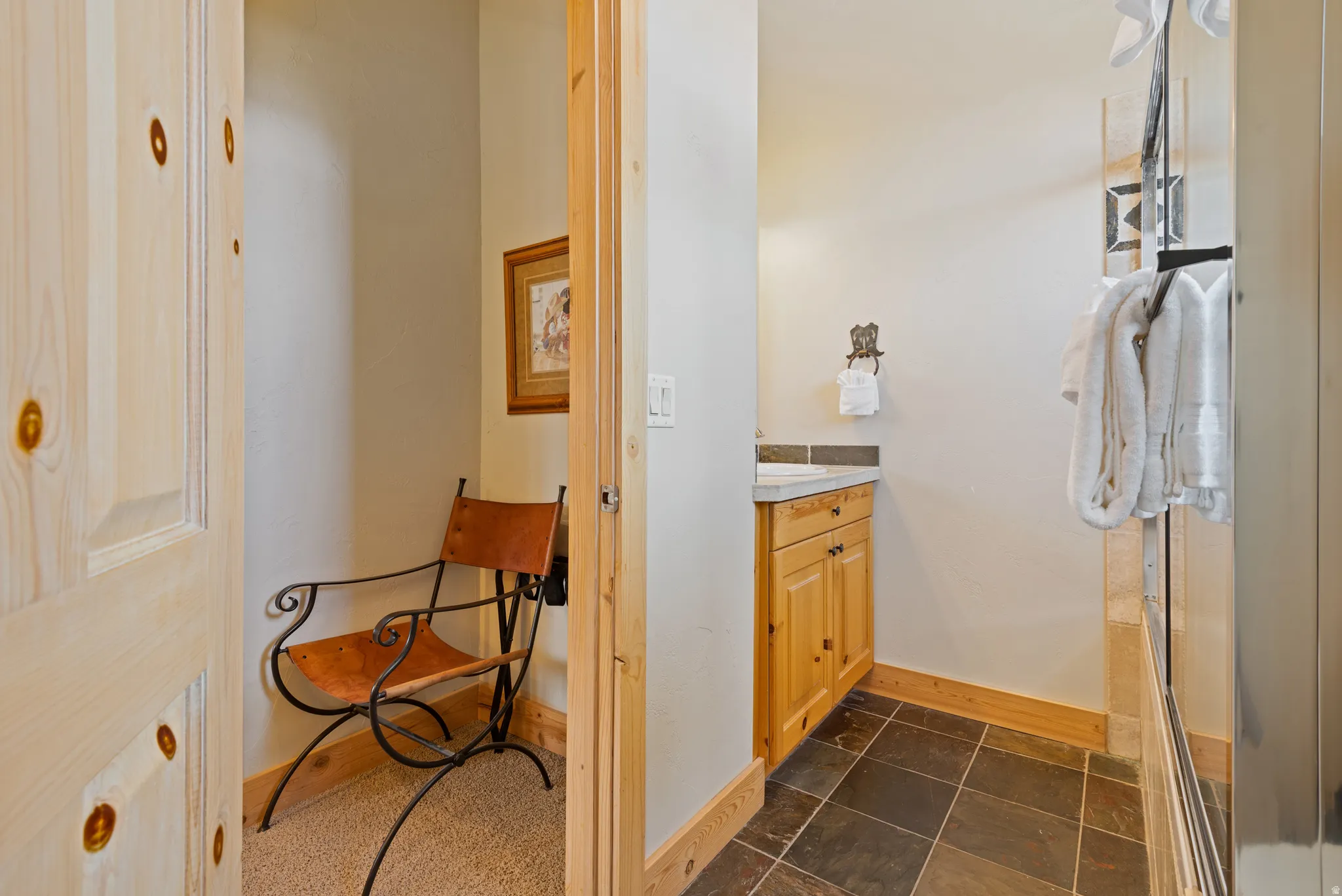 Rustic-inspired powder room featuring a wood-finish vanity with a built-in sink, stone tile flooring, and light natural wood trim