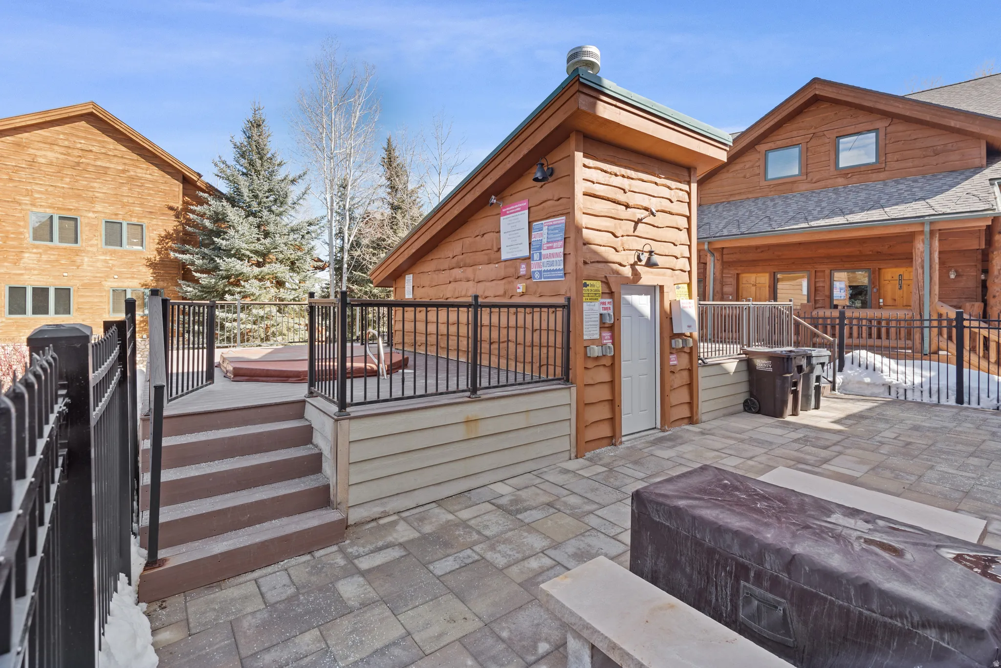 Paved patio area featuring stone pavers and a raised deck with a hot tub