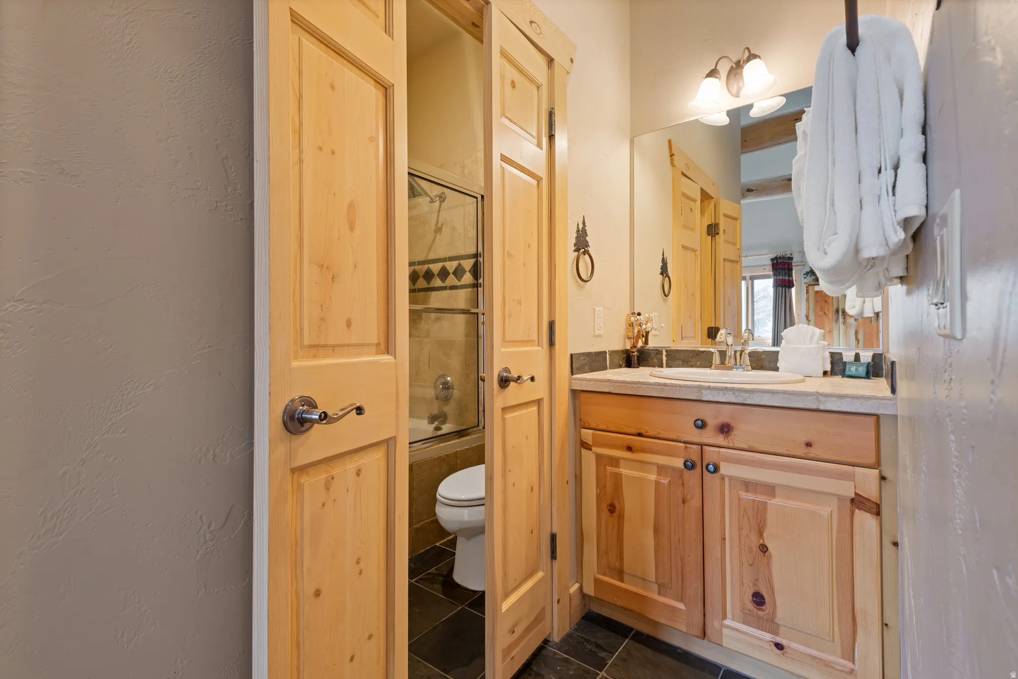 Bathroom featuring a vanity with a light-toned countertop, natural wood cabinetry, and a single basin sink