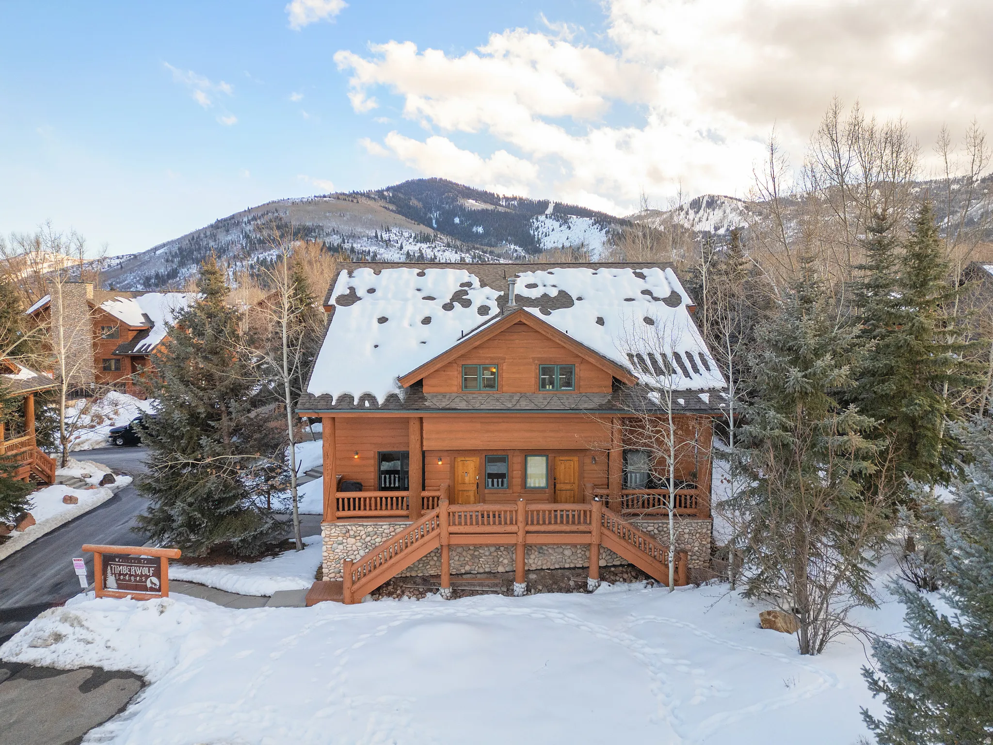 Log cabin exterior featuring a natural wood finish, stone foundation, and multiple windows